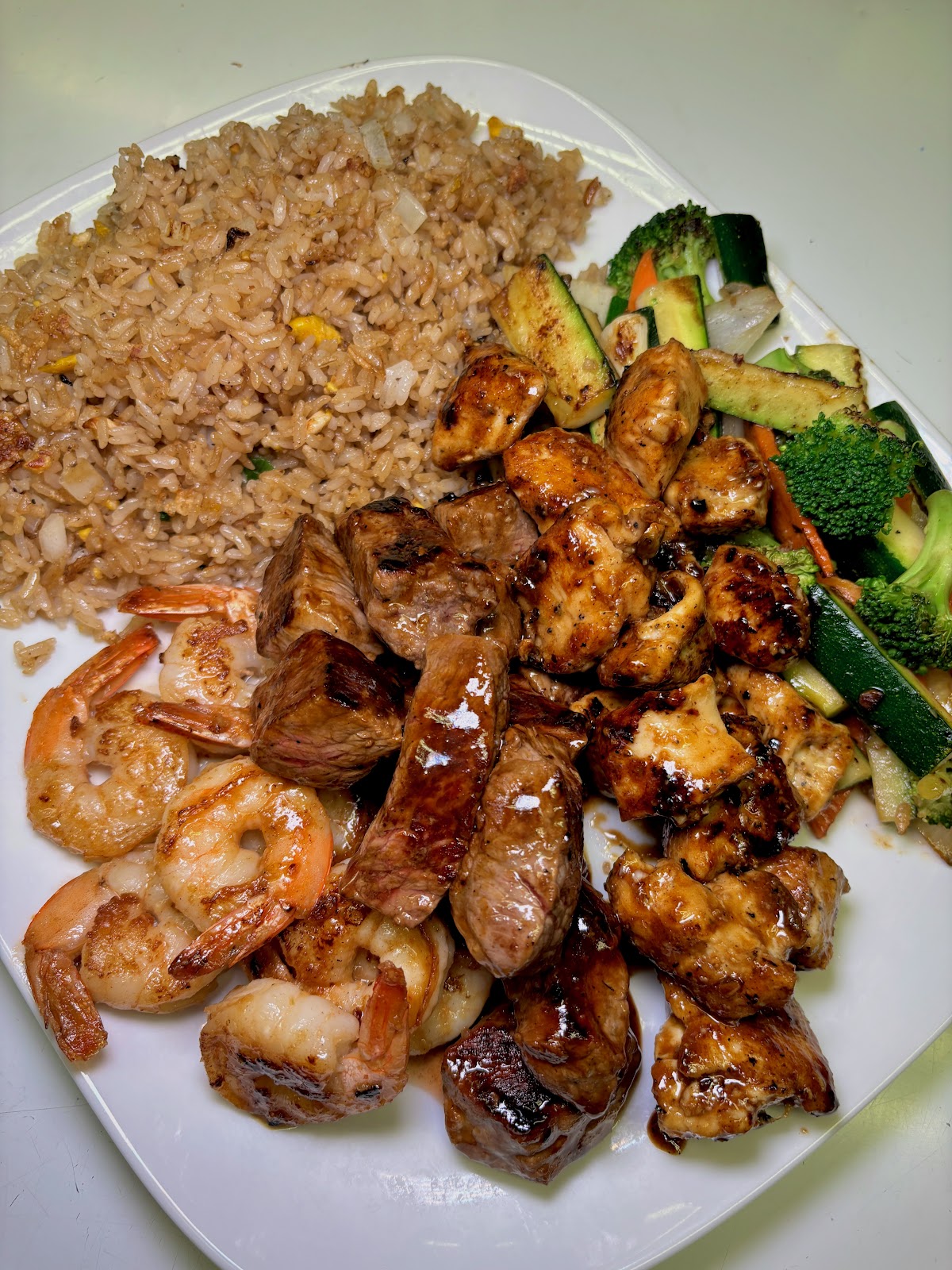 Hibachi combo plate with steak, chicken, shrimp, and grilled vegetables